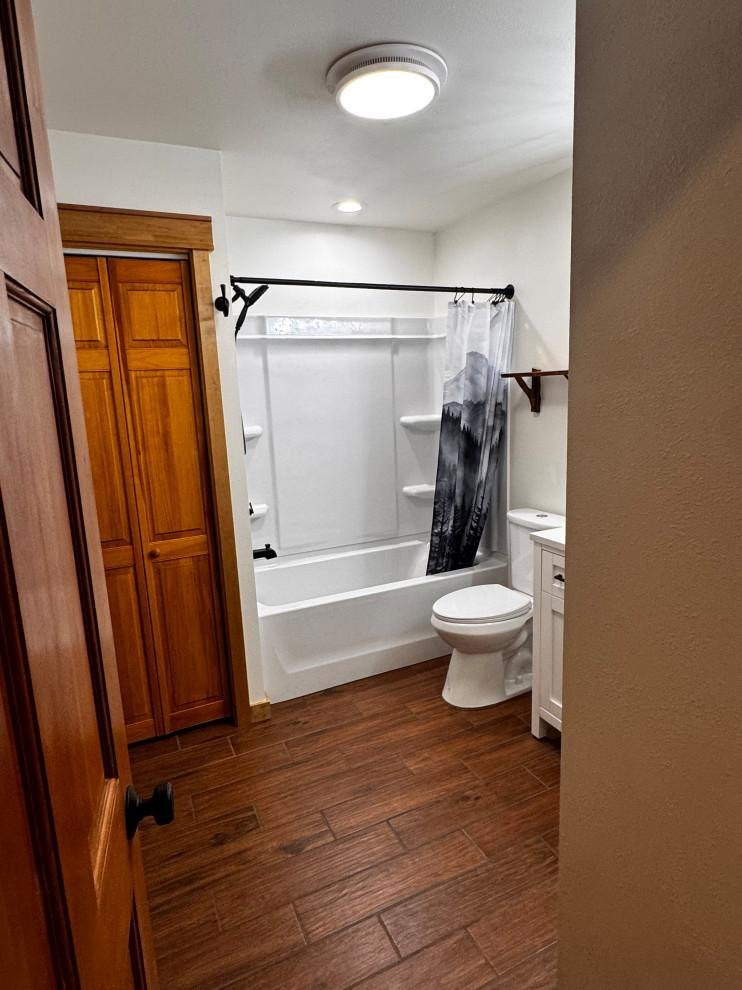 Finished bathroom with tub, tile surround and wood-look flooring